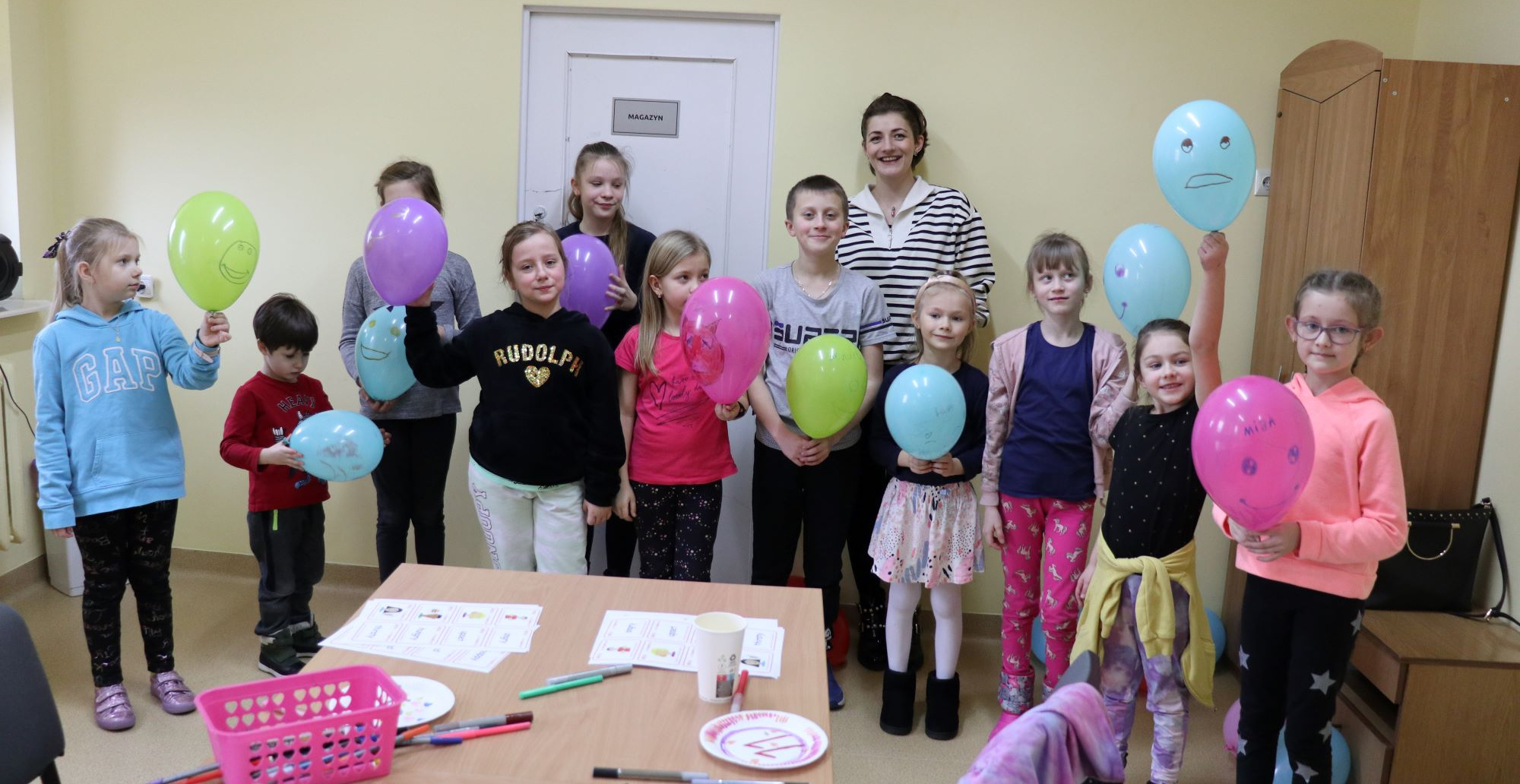 Dzieci uśmiechają się do zdjęcia trzymając w ręku baloniki.